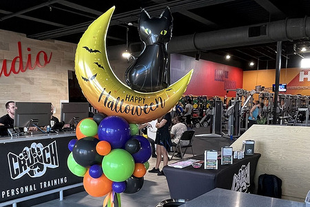 Halloween organic balloon topiary with a Happy Halloween foil balloon that features a moon and black cat on top. the colors are orange, purple, lime green and black.