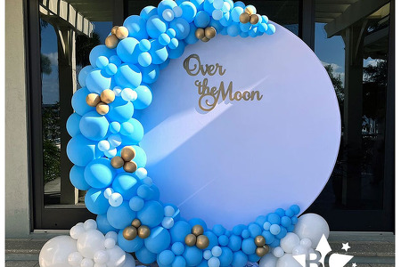 Over the Moon themed Baby Shower with round white backdrop, light blue and gold moon balloon sculpture and Over the Moon sign in gold in Merritt Island FL by Blank Canvas Event Decor