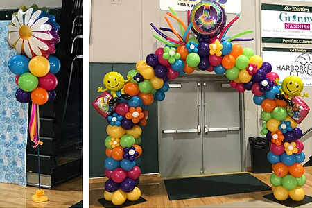 School Dance Decor For 60's theme homecoming for Melbourne FL featuring Peace and Love theme Balloon Arch, Balloon Columns and dance floor with peace sign balloon sculpture hanging over it.