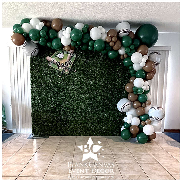 Baseball themed organic balloon garland on a fax greenery hedge backdrop with custom sign and foil baseball balloons. The colors were green, brown and white.