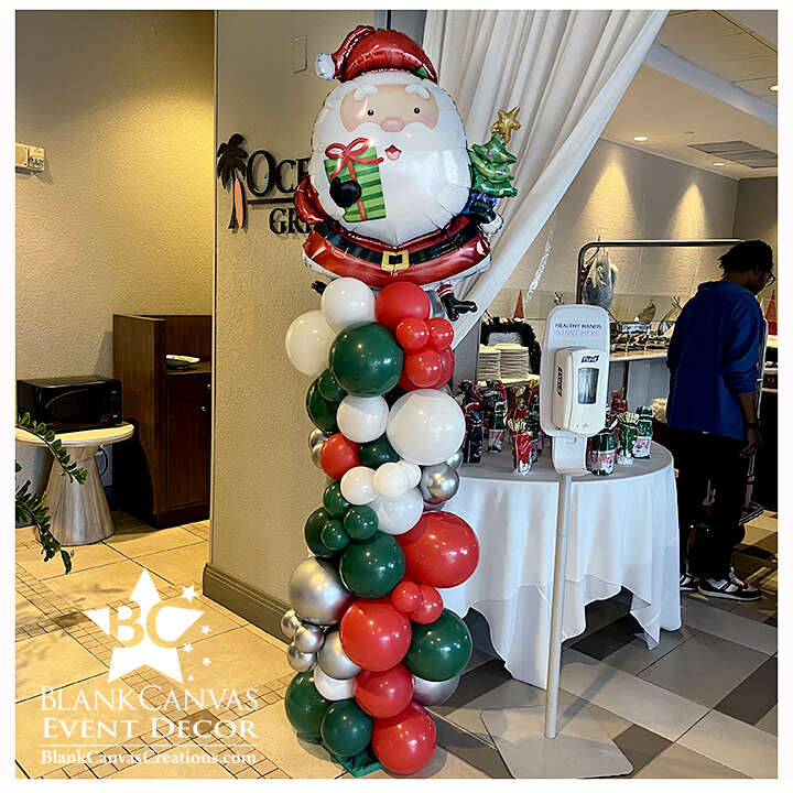 Organic Style Balloon Column with a Santa balloon on top. It features red, green, white and silver balloons a different sizes to serve as a cute entry piece.