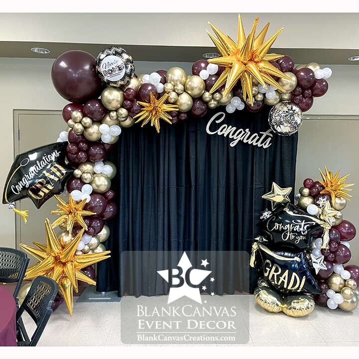 FIT Graduation Balloon Backdrop with Maroon, Gold and White organic balloons with grad foils and black fabric backdrop.  Balloons Indialantic FL
