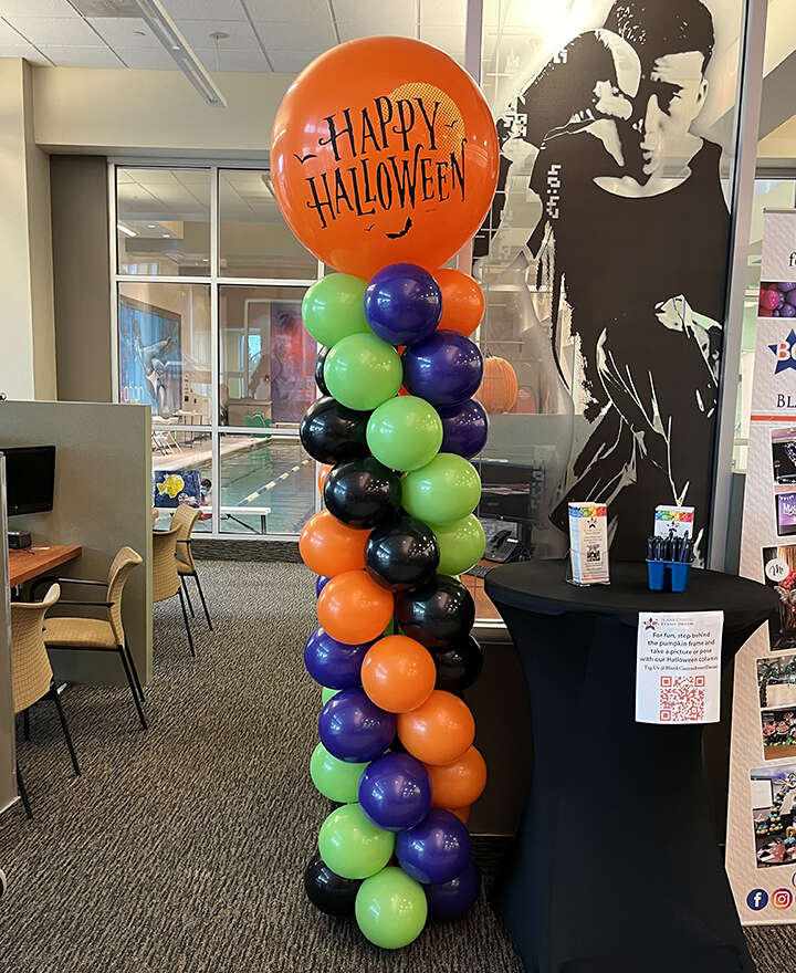 Halloween classic spiral balloon column with a Happy Halloween printed latex balloon on top. the colors are orange, purple, lime green and black.